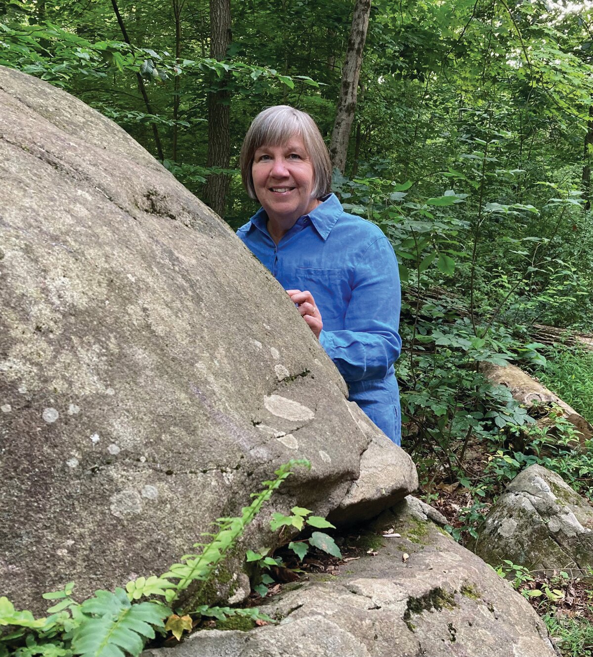 Jane McKinley stands behind one of the Sourland Mountain’s signature boulders.
