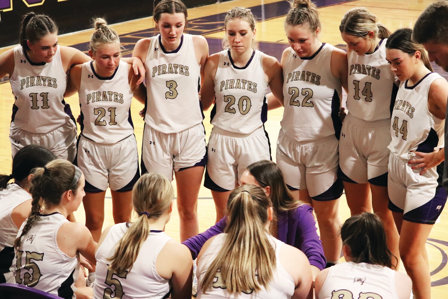 Palisades girls basketball players huddle together during a game.