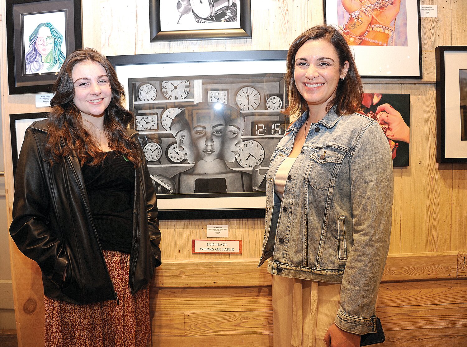 Lily Rasnake and her mother, Erin, stand next to Lily’s piece “Distractions,” the second-place winner in the Works on Paper category.