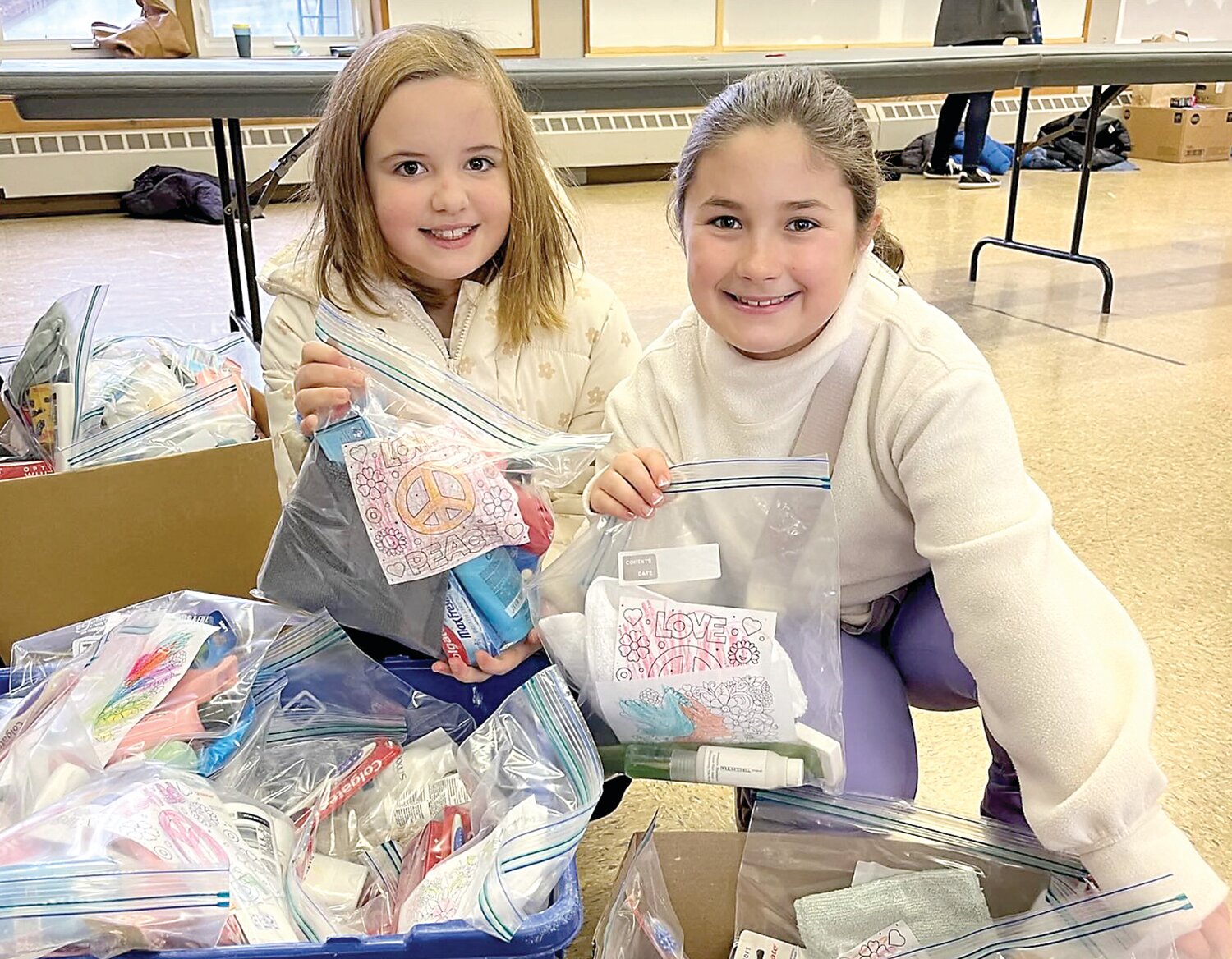 A pair of Buckingham Friends School students hold up bags of essential supplies that were donated to Bucks County Housing Group.