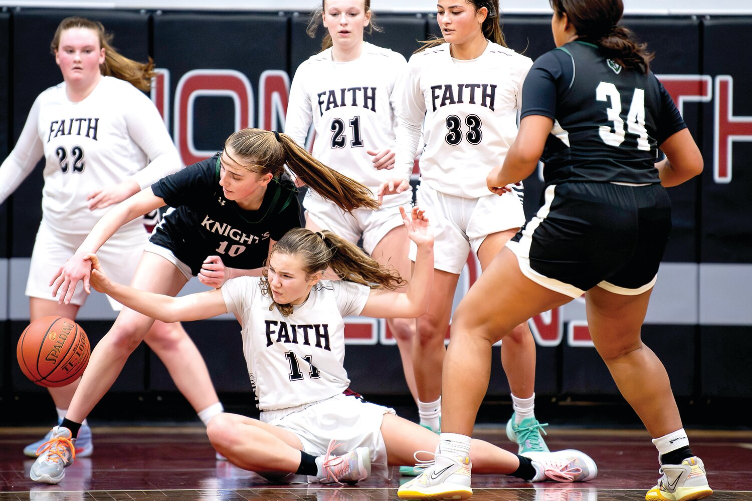 Faith Christian’s Aubrey Sauers tries to gather a loose ball after getting knocked to the court.