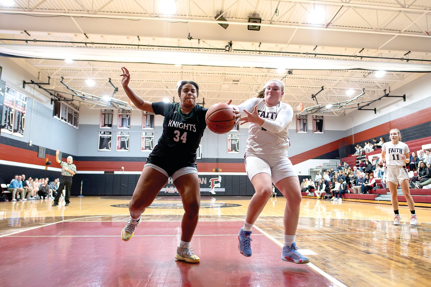 Faith Christian’s Kendal Robison and Delco Christian’s Ashanti Harris battle for an inbound pass under the basket in the first half.