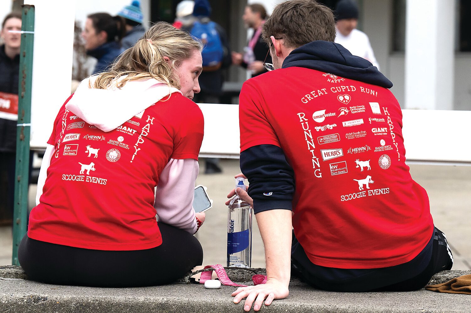 Two participants relax as they watch families gather to take part in the Great Cupid Run.
