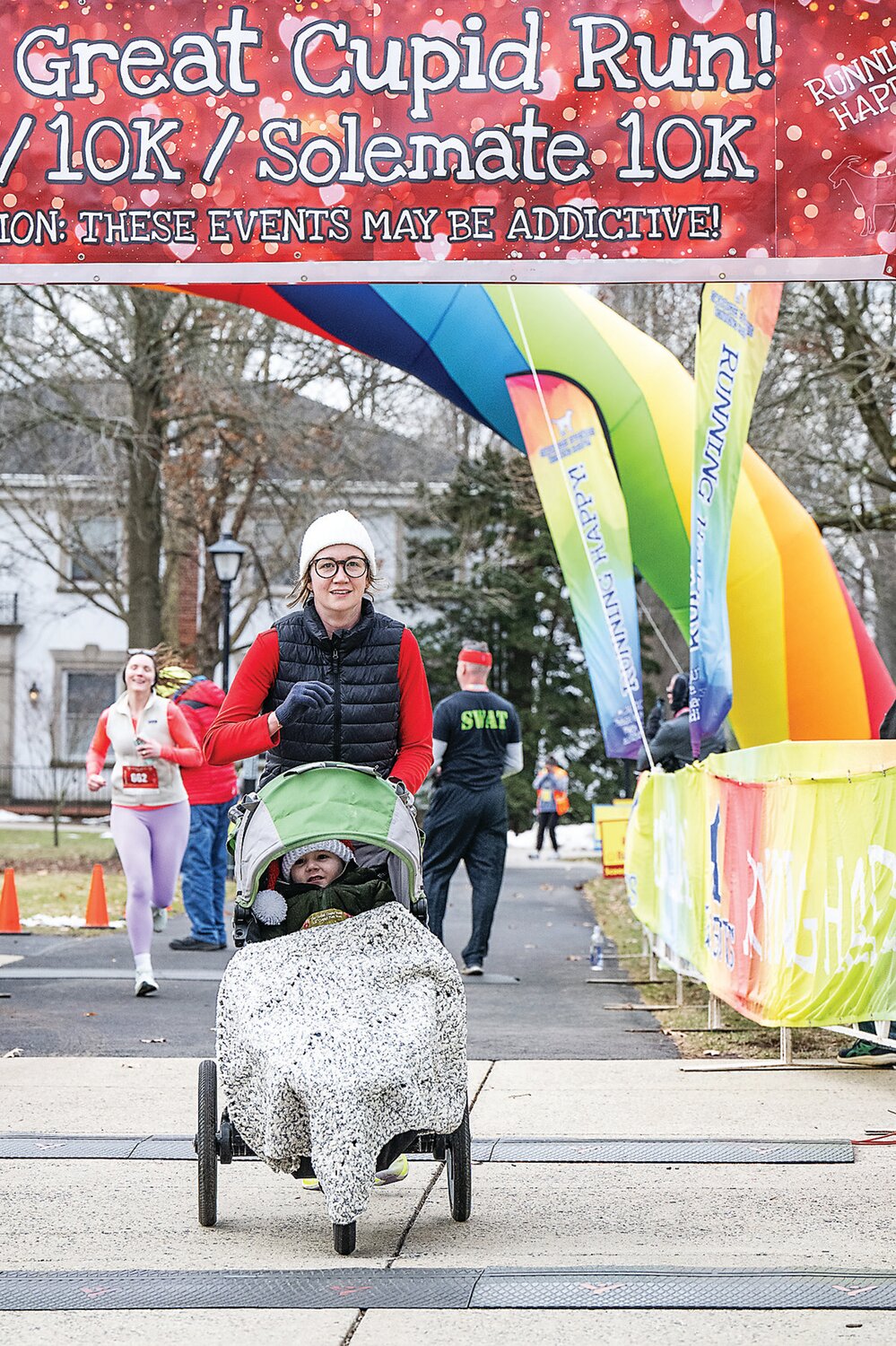 A mother running and pushing a stroller makes her way across the finish line.