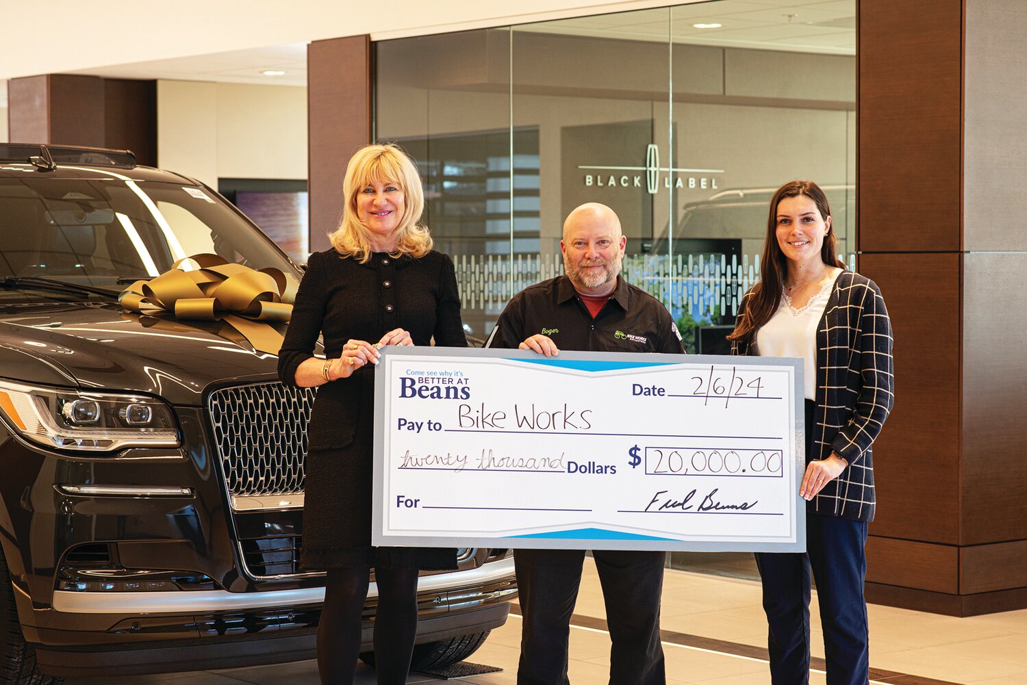 From left, Beth Beans Gilbert, vice president of Fred Beans Automotive Group; Brian Boger, team director of Bike Works p/b Fred Beans Elite Cycling Team; and Tess Kemmerer, of Fred Beans, renew the partnership between Beans and Bike Works with a $20,000 donation from the Fred Beans Charitable Foundation.