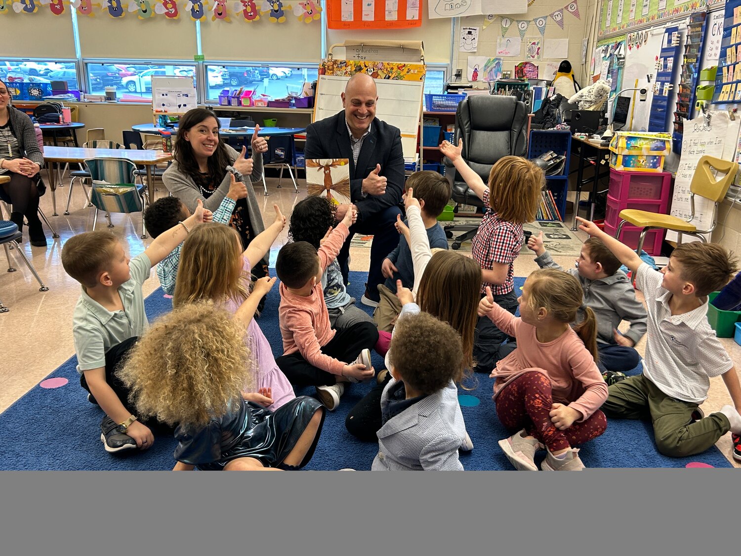 Pennridge Communications Director David Thomas reads a story at Sellersville Elementary School and gets a thumbs-up from kindergarten teacher Jackie Brown and her students.
