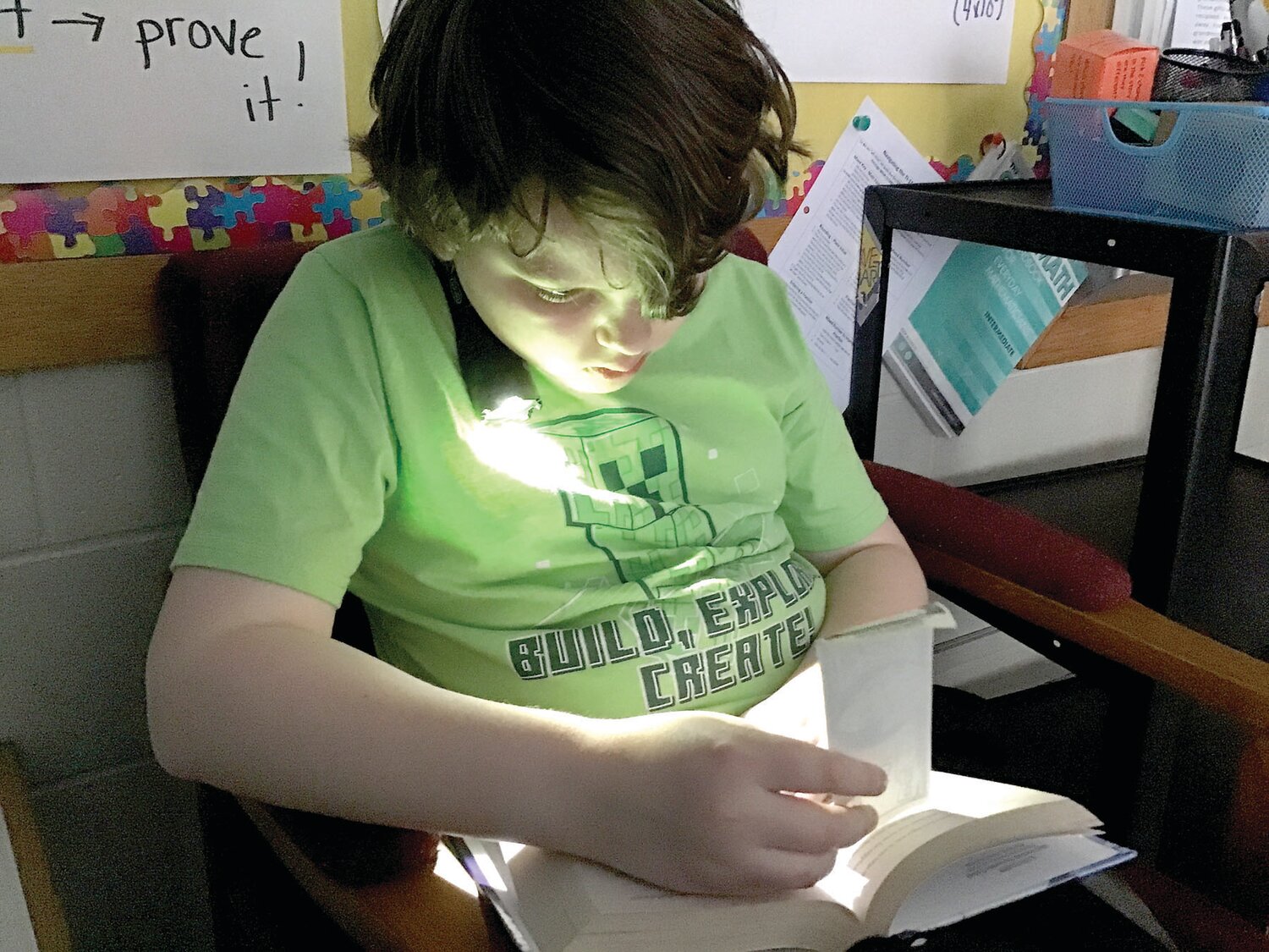 Charles Sammons, a fifth grader at West Rockhill Elementary School, reads by flashlight.