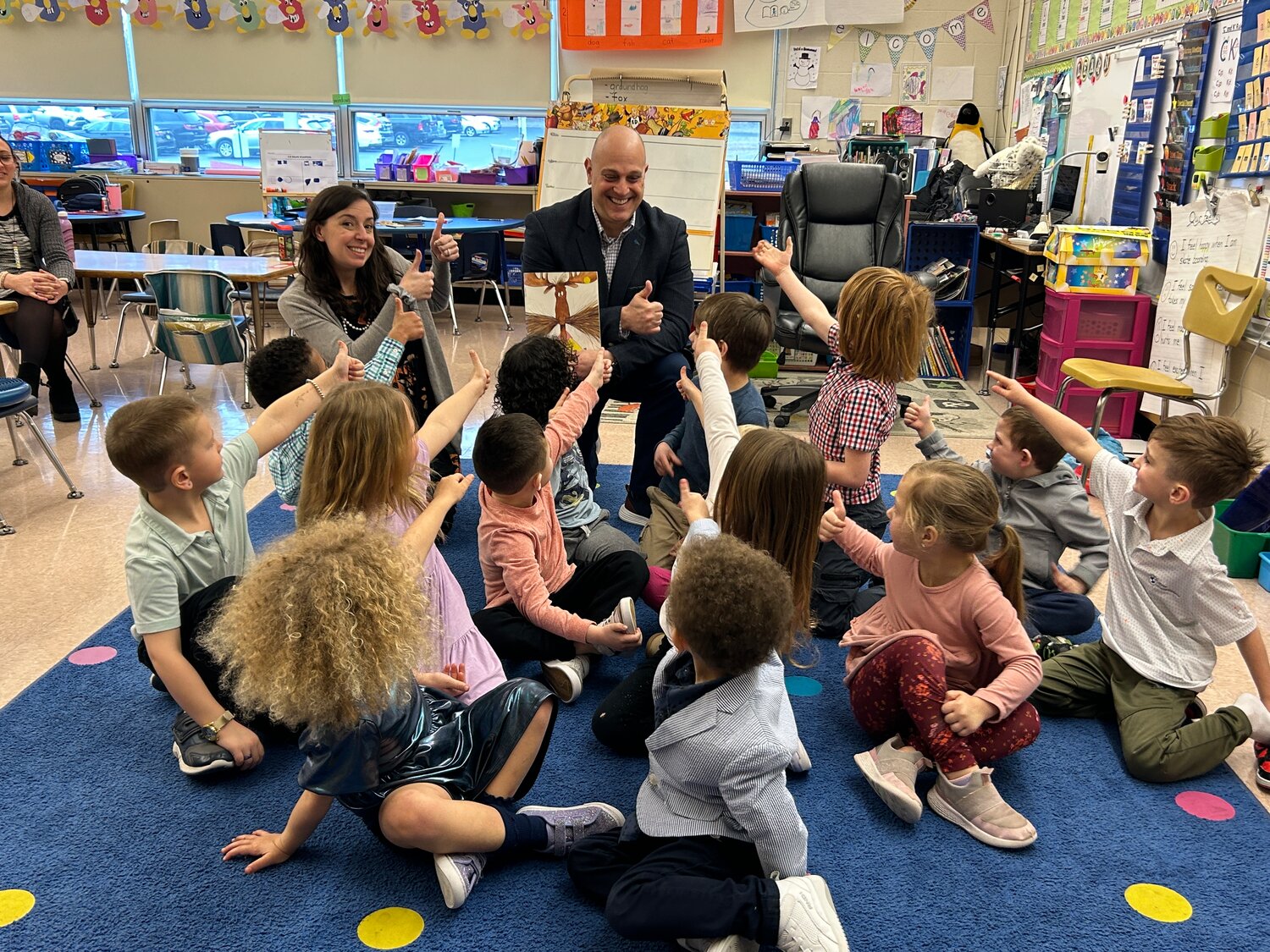 Pennridge Communications Director David Thomas reads a story at Sellersville Elementary School and gets a thumbs-up from kindergarten teacher Jackie Brown and her students.