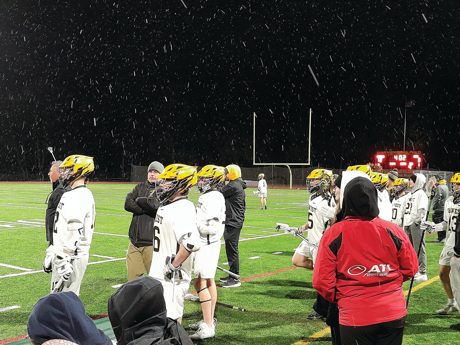 Snow flurries fall on members of the CB West boys lacrosse team during the Bucks’ Monday night win over Lower Merion.