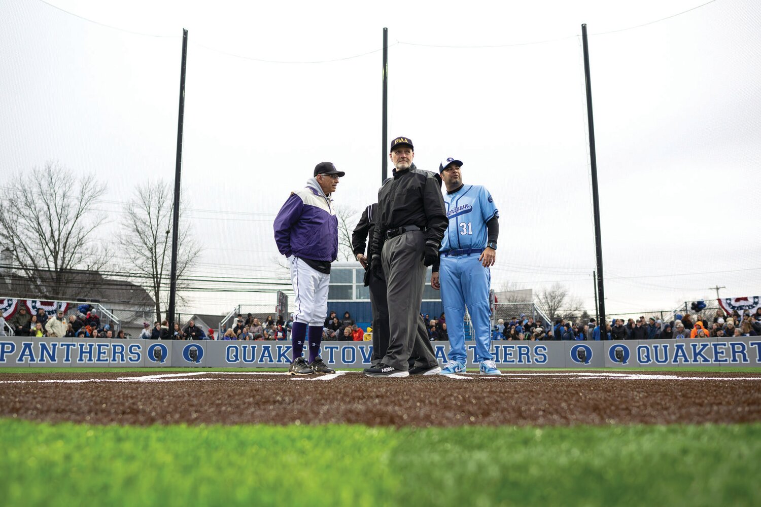 Perkiomen School coach Kendall Baker and Quakertown coach Jon Pallone meet at home plate with the umpires for the new field’s ground rules.