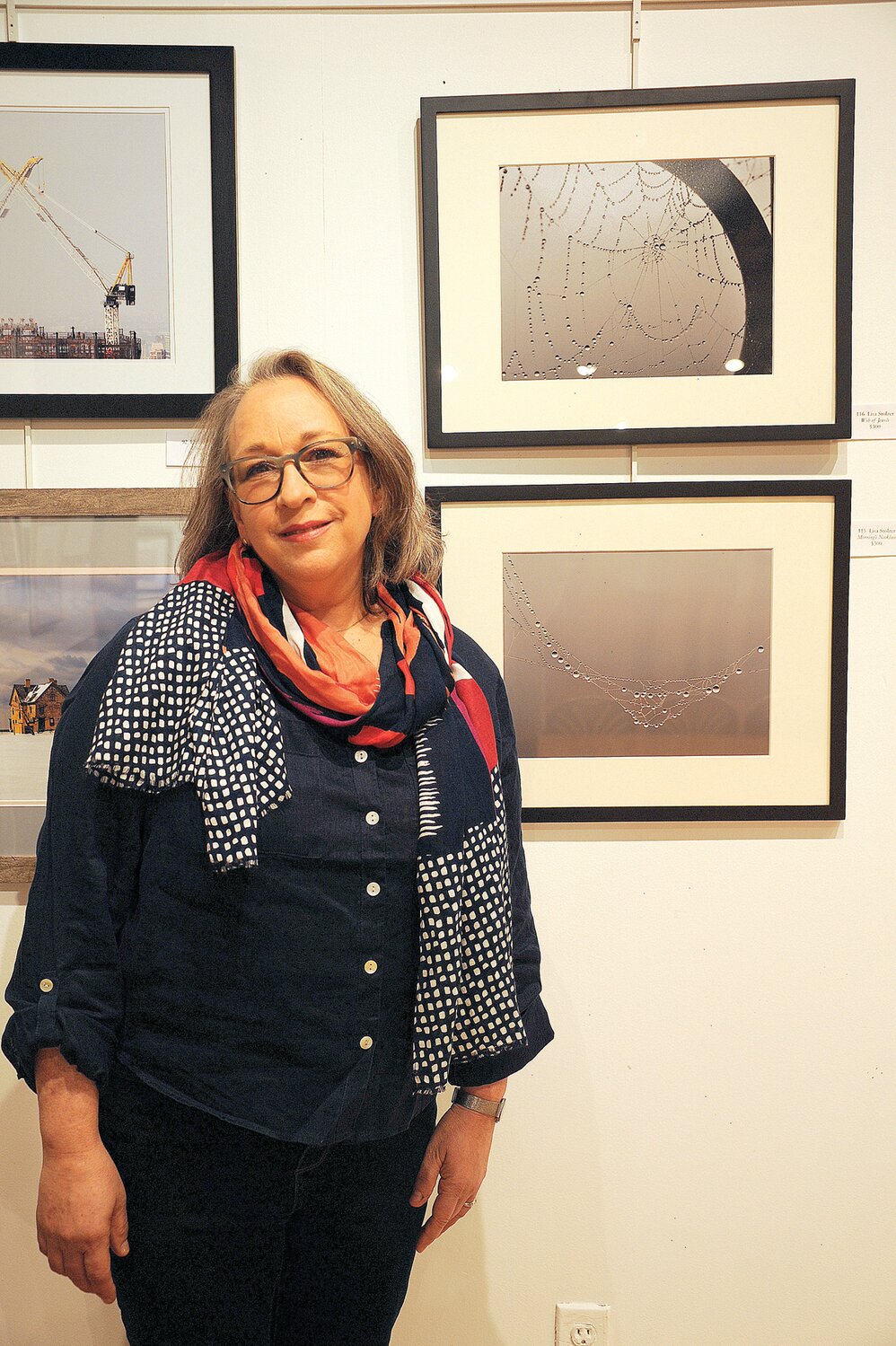 Lisa Stolzer next to her photographs, “Web of Jewels” and “Morning’s Necklace,” which won the Nature Award.