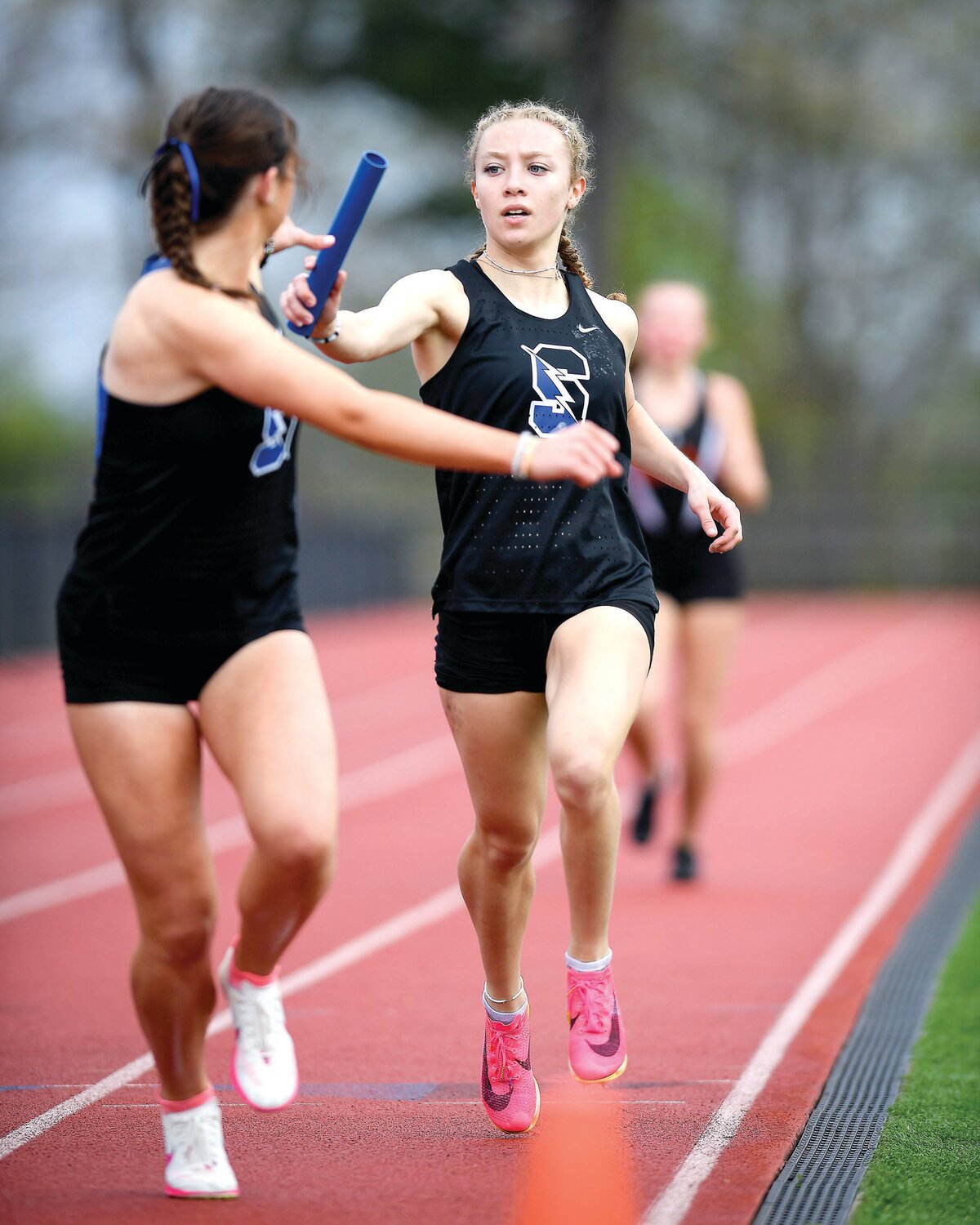 Central Bucks South’s Taryn Kotsur passes the baton to anchor Riley Rooney in the girls 4x1,600. CB South would win first place with a time of 21:28.