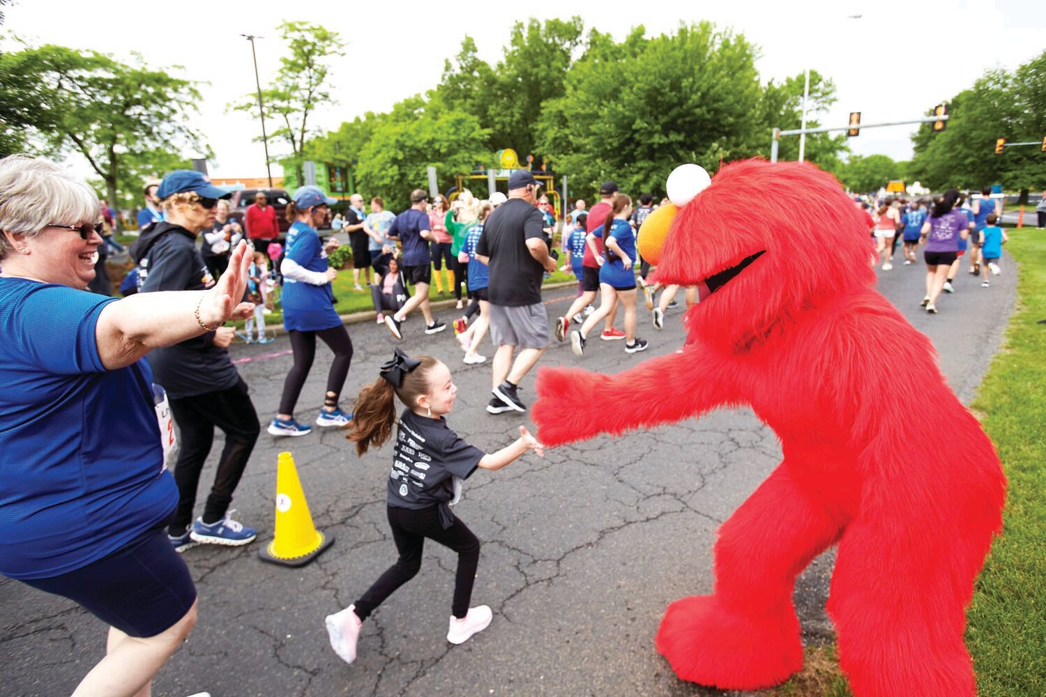 Elmo slaps hands with a youngster during the Sesame Place Classic May 19.