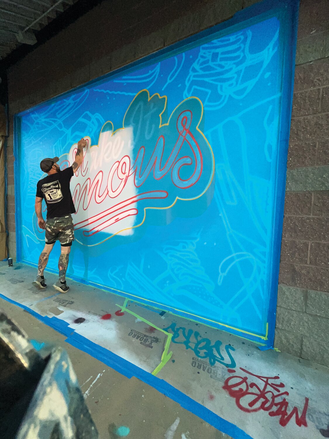 Jimmy McMenamin of Glossblack LLC, creates a mural on the side of the Famous Footwear store in the Warminster Towne Center.