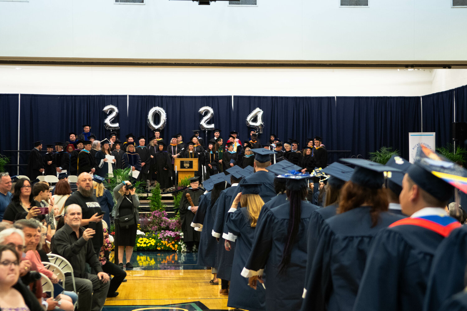 Graduates process into the gymnasium at the Newtown campus of Bucks County Community College for their commencement on May 16.