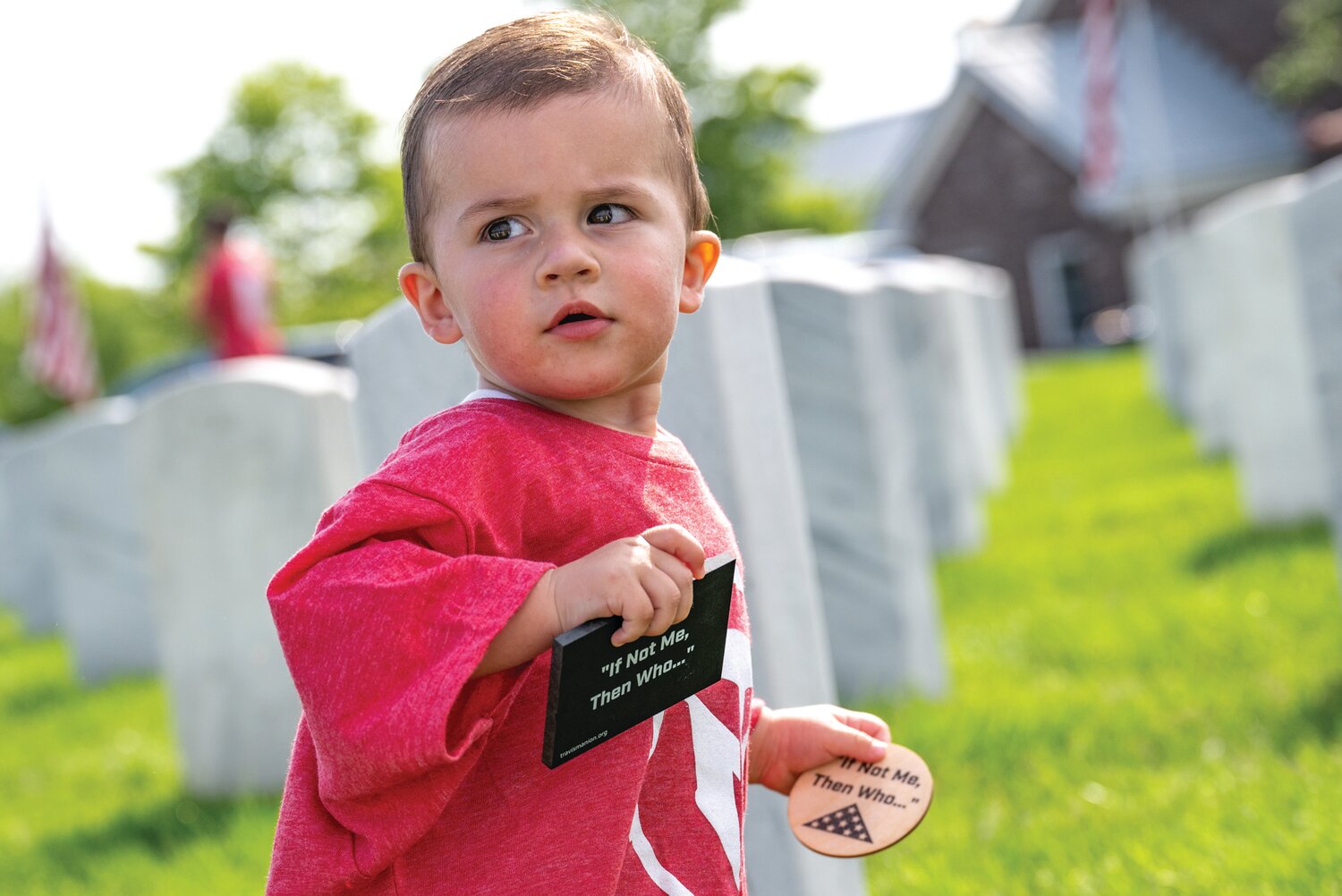 Leonardo Pellicore, 14 months, holds tokens that were placed on the graves of service members at Washington Crossing National Cemetery.