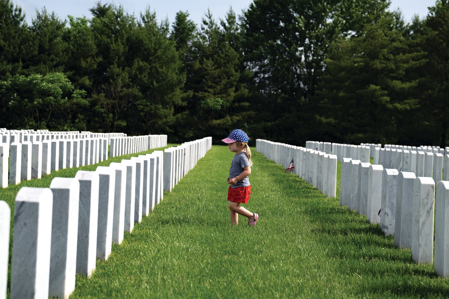 Donning a patriotic hat, a young child walks through Washington Crossing National Cemetery on Memorial Day.