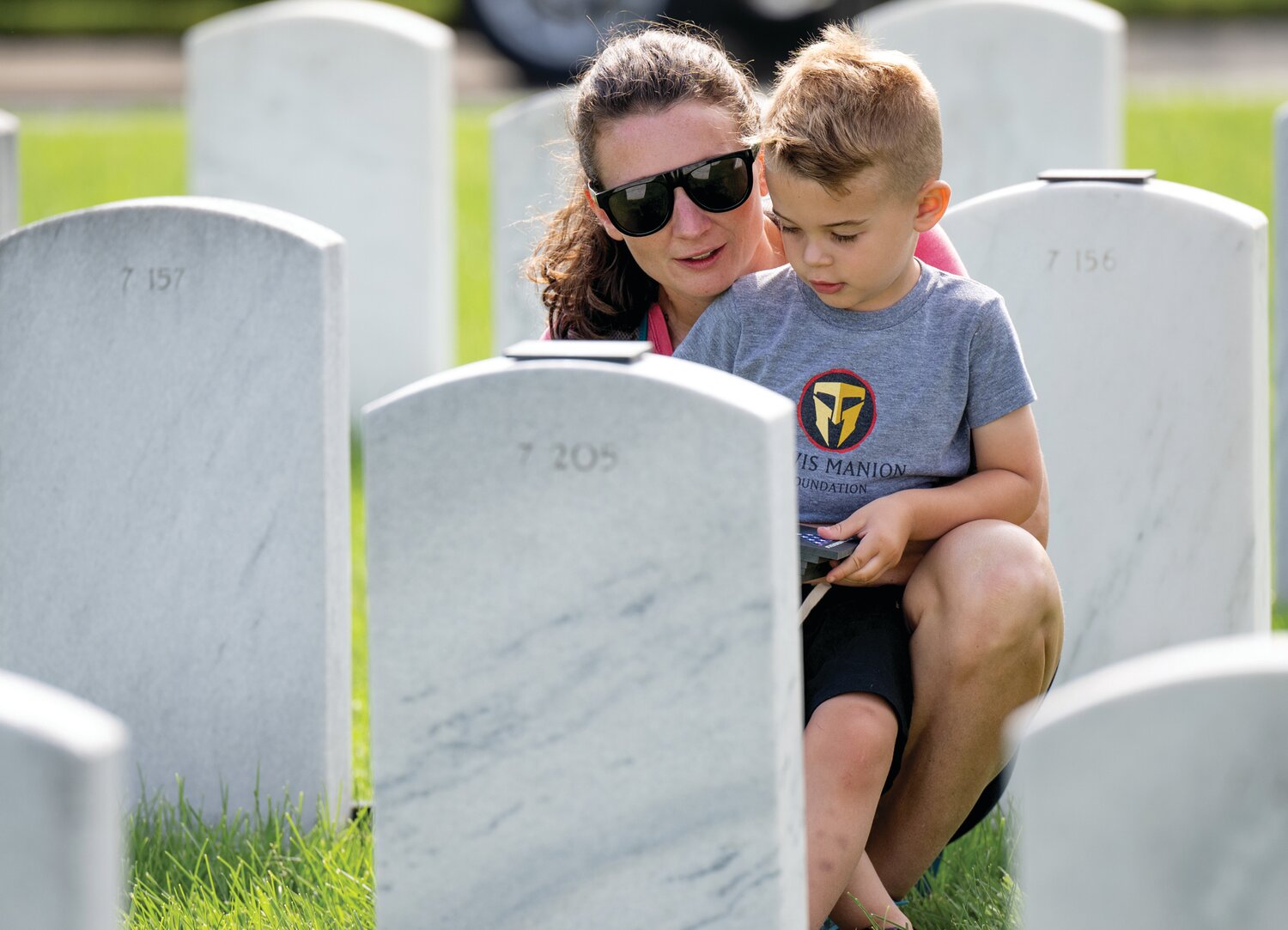 Anthony Ferrero, 4, and his mother, Ashley Ferrero place handcrafted tokens on the graves of fallen heroes at Washington Crossing National Cemetery.