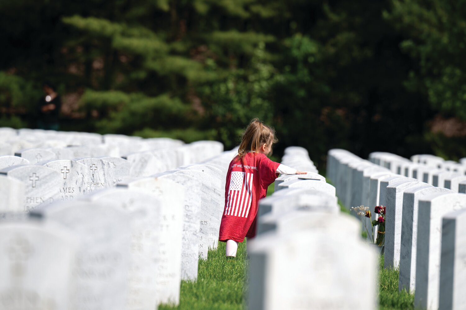 Sydney Heffron, 4, of New York, who participated in The Honor Project event with her uncle and aunt, Brian and Lauren Joyce of Doylestown, places her hand on one of the gravestones at Washington Crossing National Cemetery.