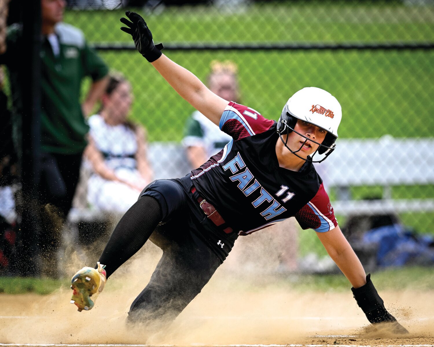 Faith Christian’s Lexi Reed slides safely after scoring the game’s first run.