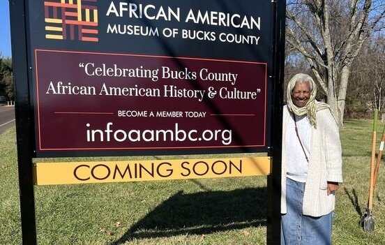 Linda Salley, president and executive director of the African American Museum of Bucks County, poses in front of the sign where the museum will be at the Boone Farm in Middletown Township.