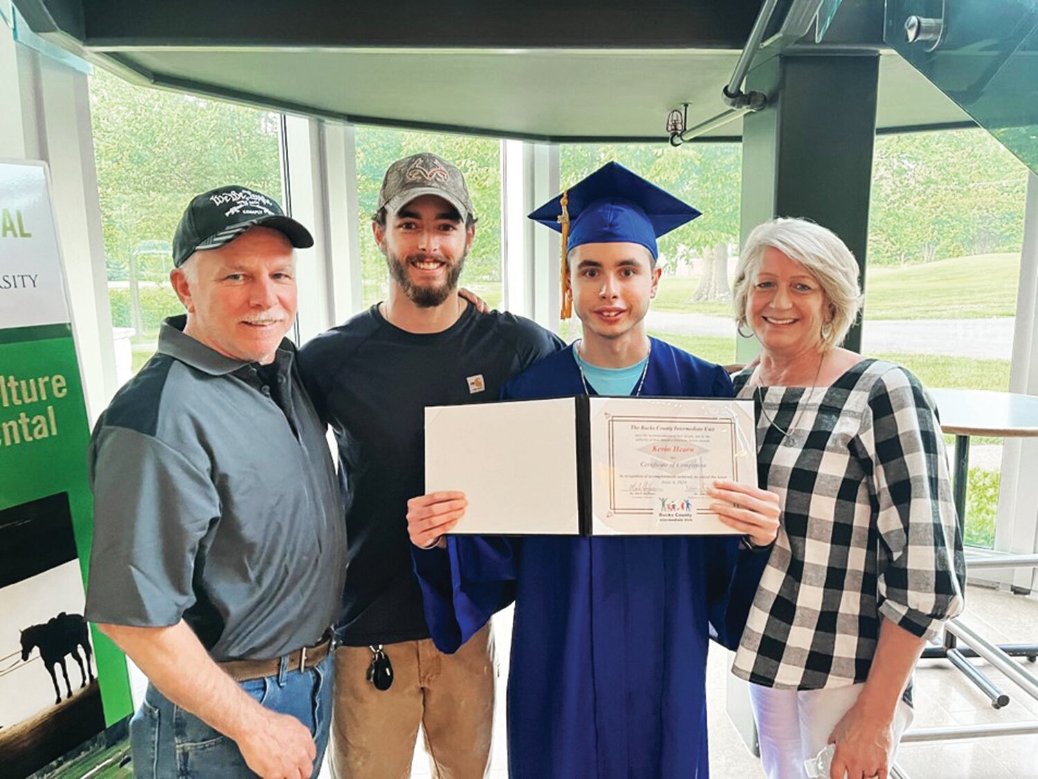 Kevin Hearn, surrounded by his parents and brother, holds up his graduation certificate.