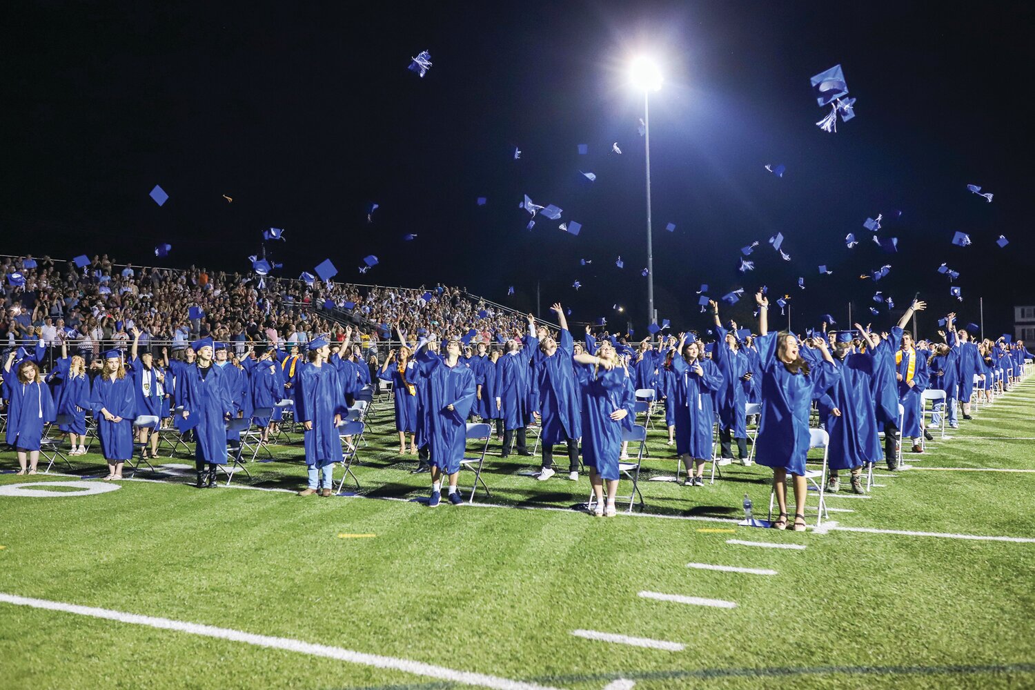 Students toss their caps into the night sky during Quakertown’s 2024 graduation ceremony.