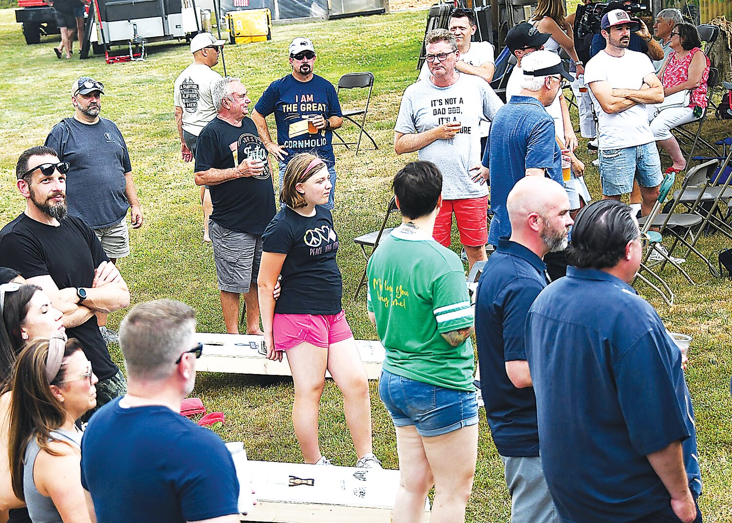Participants and spectators listen to the list of teams for the cornhole tournament.