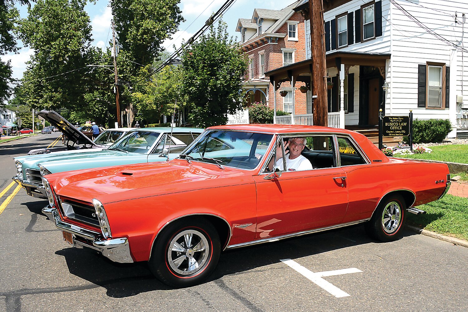 A car owner waves during a prior Newtown Antique & Classic Auto Show. This year’s show is scheduled for July 28.