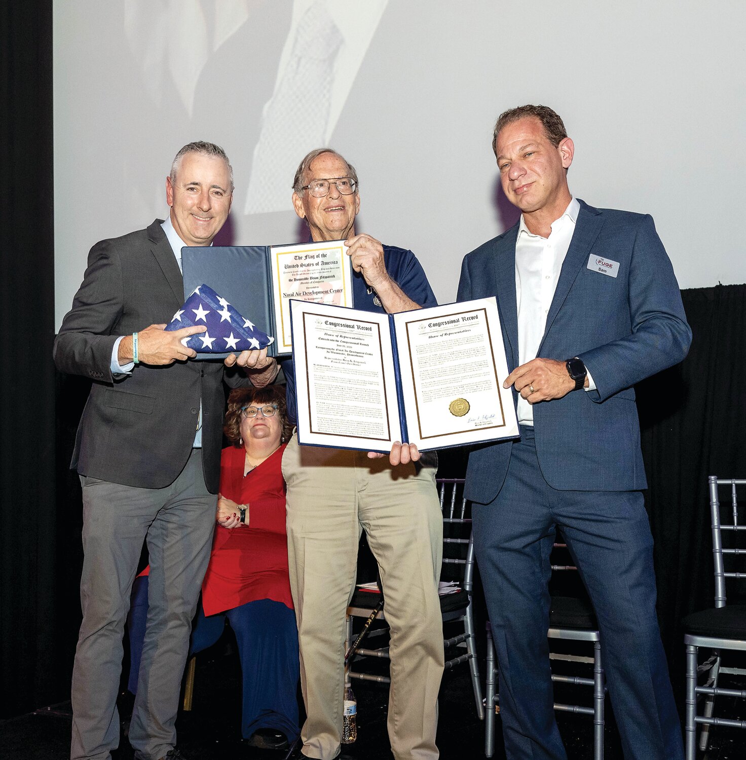 U.S. Rep. Brian Fitzpatrick, left, presents a flag and Congressional proclamation celebrating the Naval Air Development Center to William McCracken and Sam Cravero.