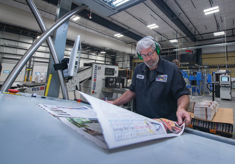 Pressroom manager Ronnie Hampton scans a paper at the console to check for any errors or issues with printing. (Photo by David Weaver/Community Impact Newspaper)