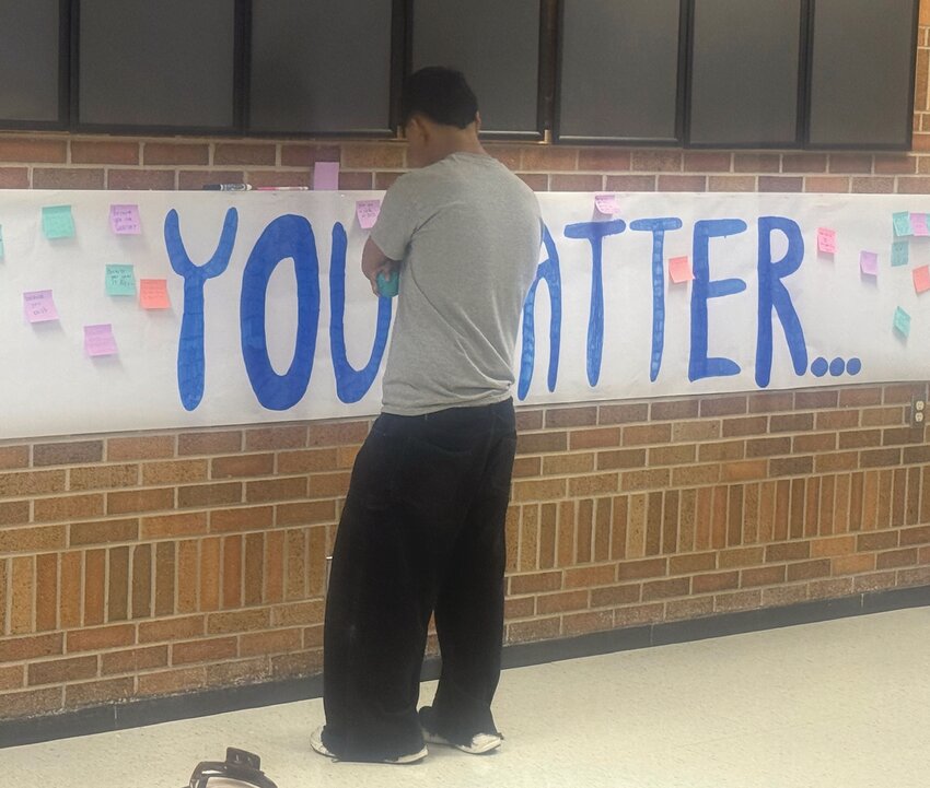 Banners with positive messages hung on the walls with post-it notes of messages from fellow students and staff. Here, one student reads the messages on the “You matter…” banner.