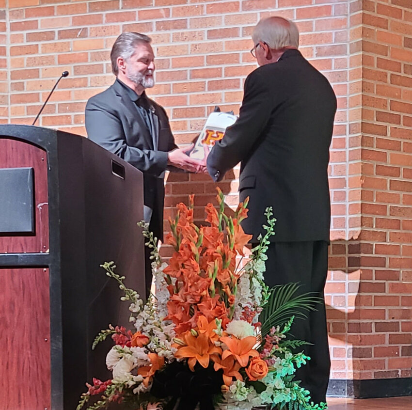 Joe Mahowald presents Milo Pietz with his Hall of Fame induction honorarium, an engraved, insulated tumbler. Pietz is the first inductee into the Huron High School Fine Arts Hall of Fame.