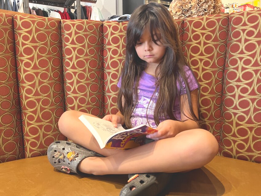 Gianna Cisneros, 9, eagerly reads her book this past Friday during her day off from school. At a time when many kids carry phones or devices, her excitement to get back to reading her book was a rare and heartwarming sight, especially as more parents and government entities raise concerns about the addictive nature of screen time.