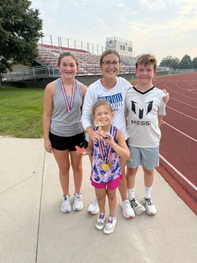 Tara Mills is flanked by her children after winning the Predictor Mile on July 30. Pictured, from left, Anna, who won the Predictor 400; Tara, Maddy, holding her mother's trophy, and Max.